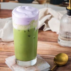 Lavender sweet cream cold foam layered with an oatmilk matcha latte in a tall glass.