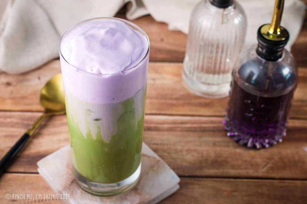 Lavender sweet cream cold foam layered with an oatmilk matcha latte in a tall glass.