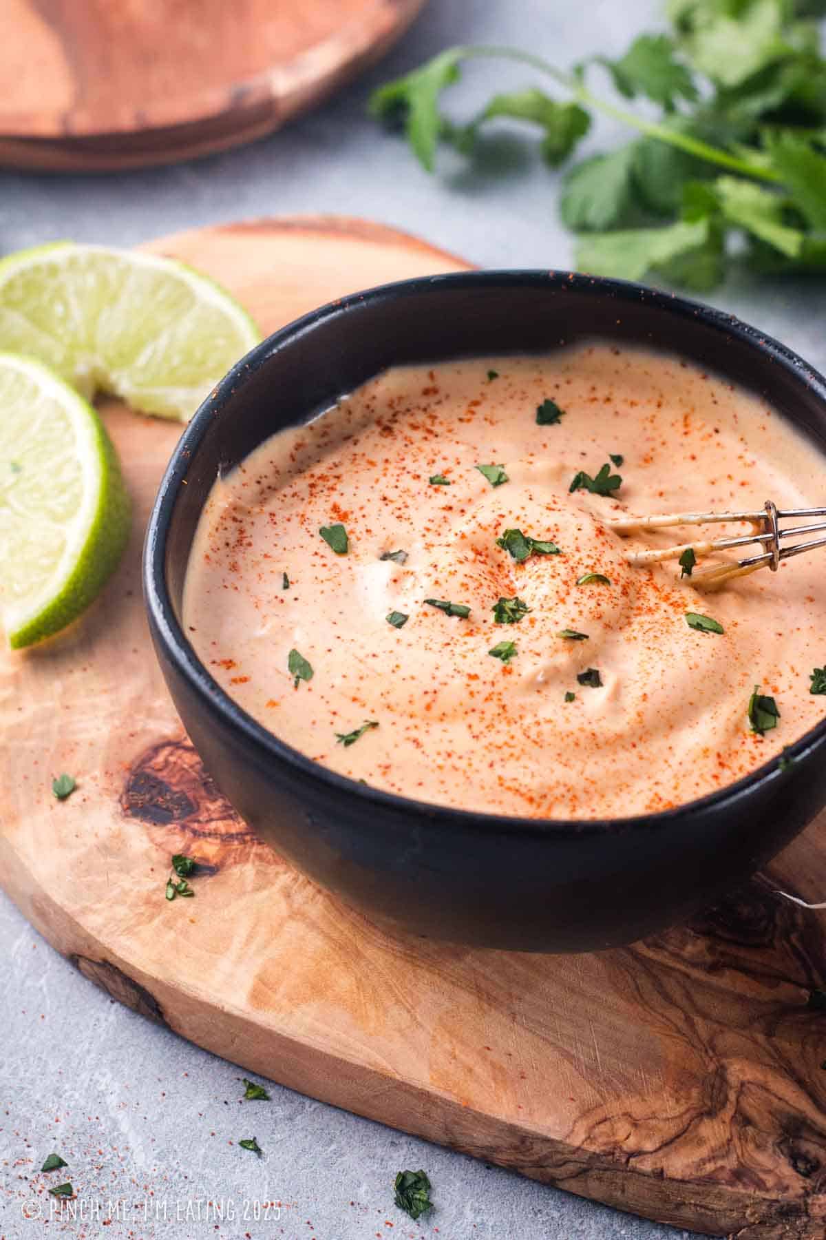 Chipotle aioli sauce in a small black bowl with a whisk.