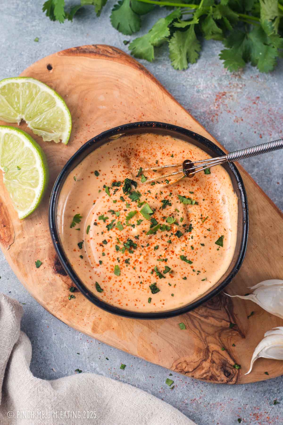 Overhead view of sauce in a black bowl on a wooden board.