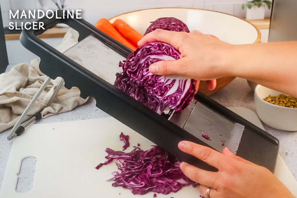 Shredding purple cabbage with a mandoline slicer.