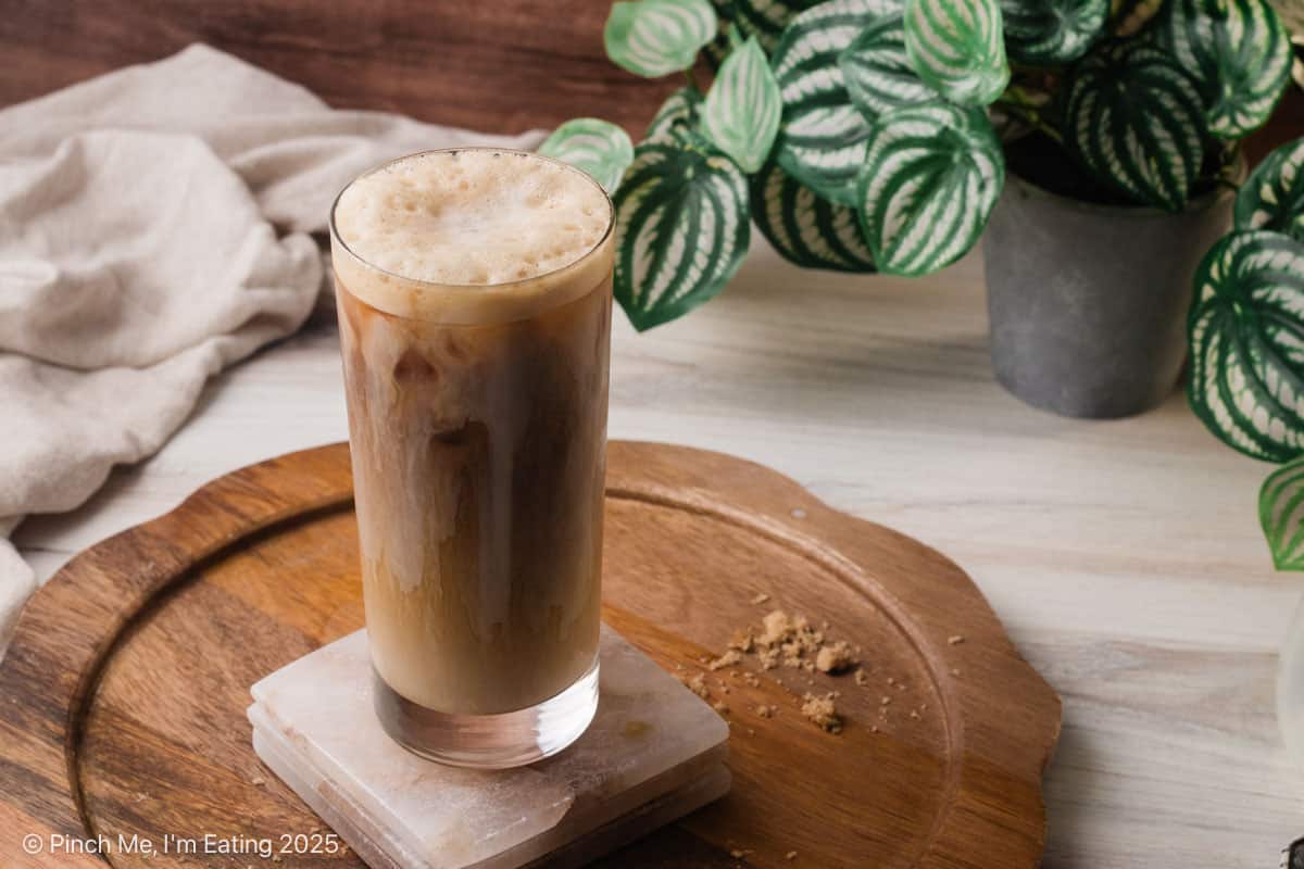 A foamy iced coffee drink on a coaster.