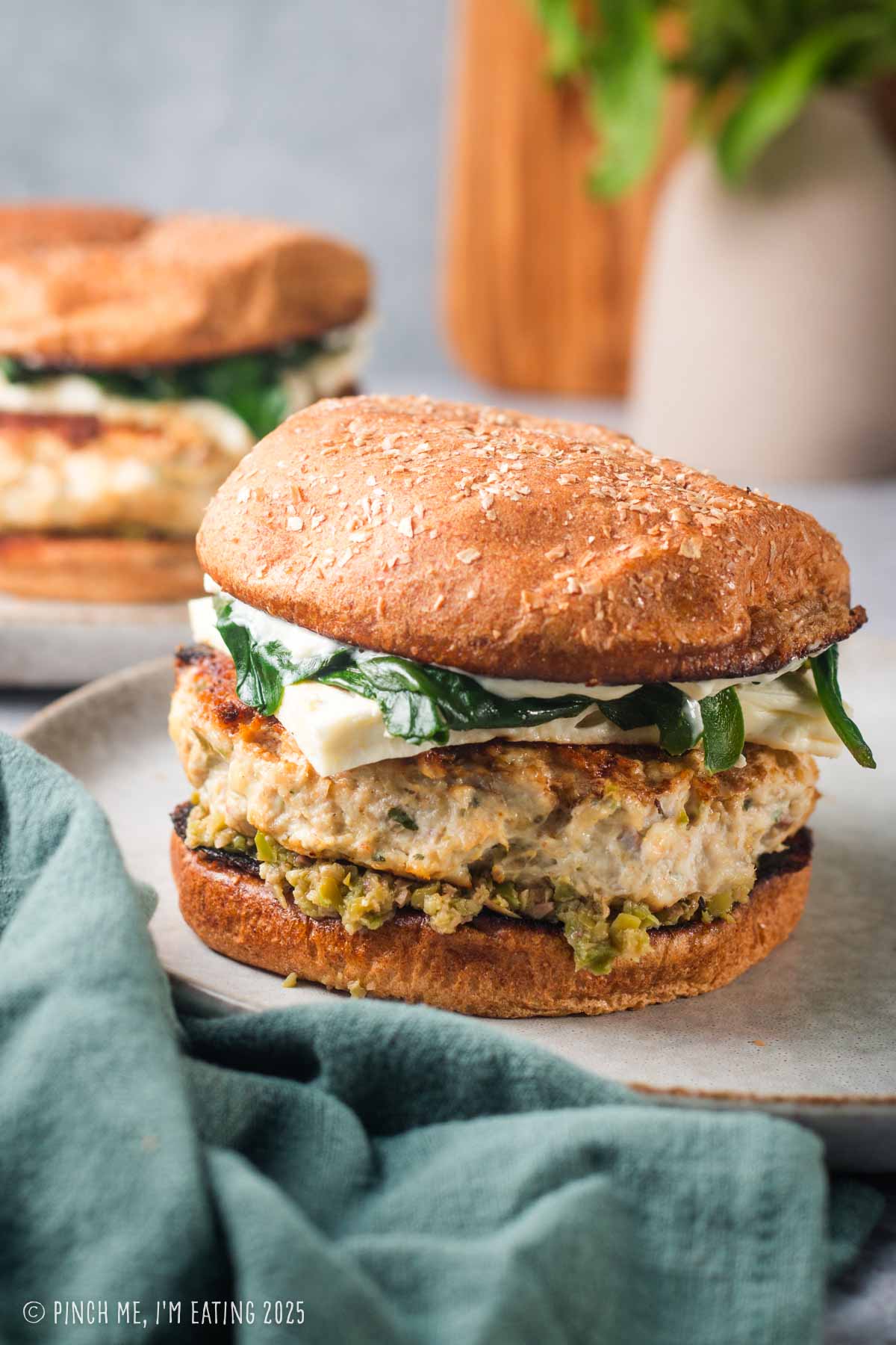 A chicken burger with olive tapenade and spinach on a plate.