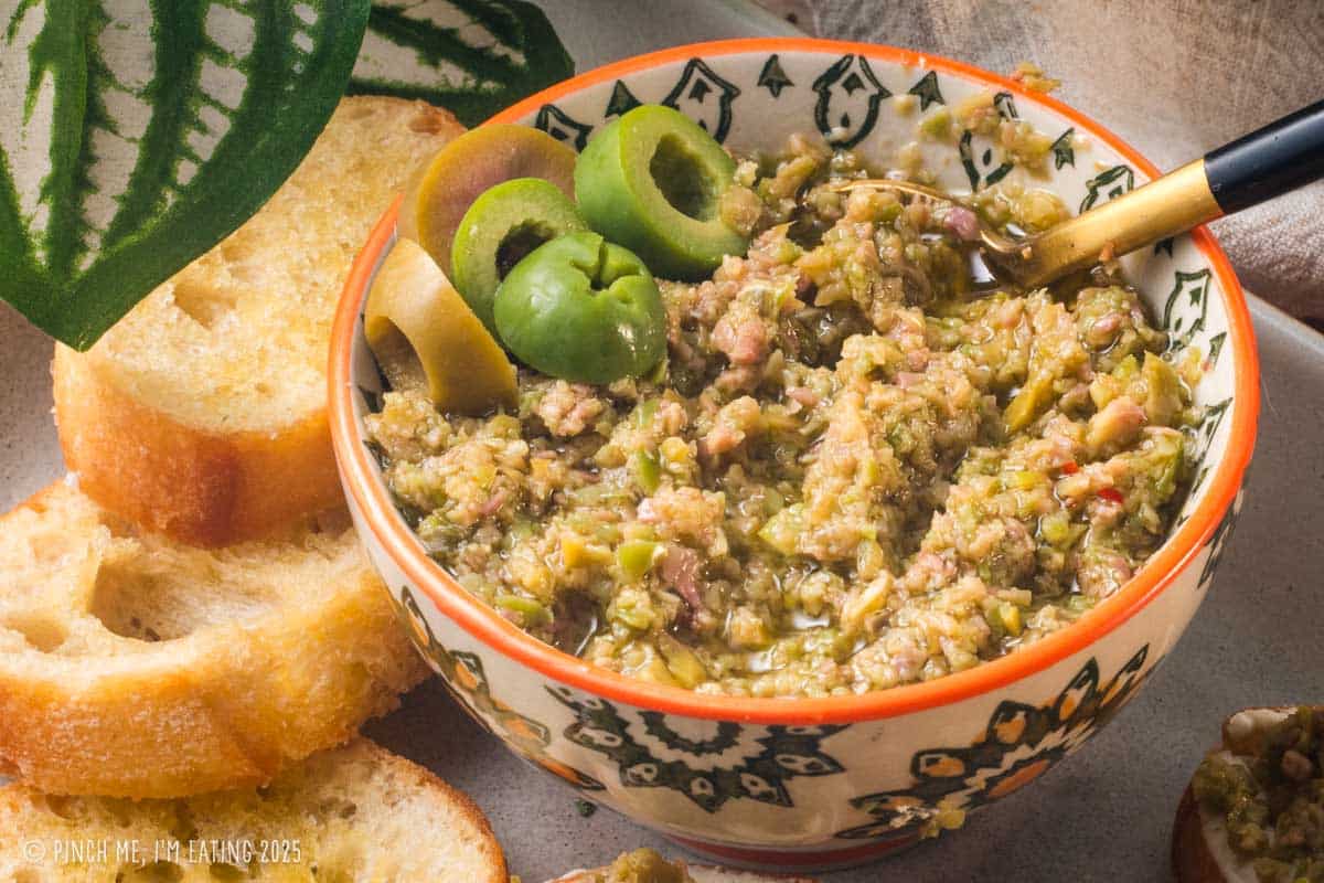 Olive tapenade in a small bowl with crostini.