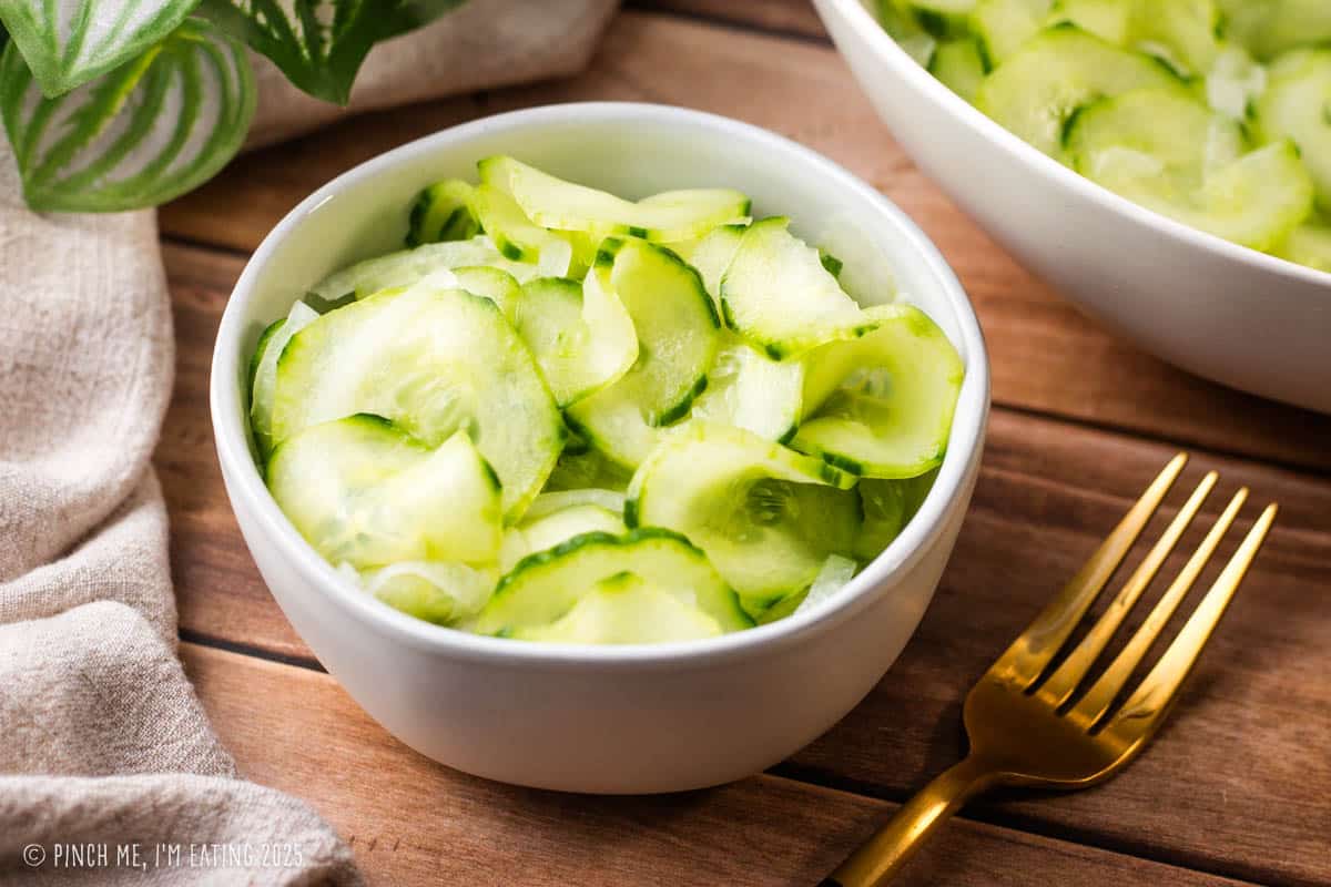 Cucumber salad in a small white bowl.