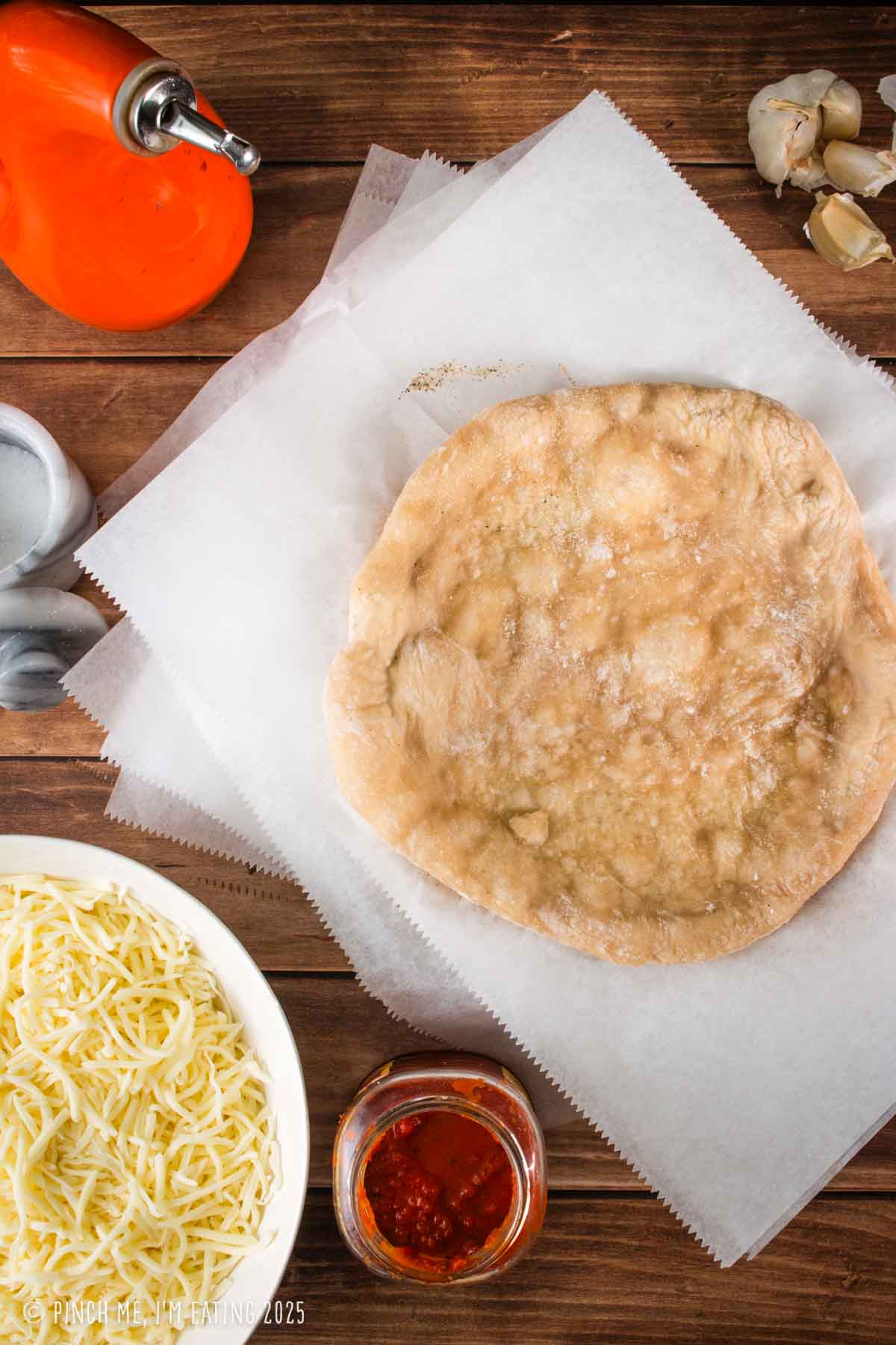 Parcooked pizza crusts stacked with parchment paper between each crust.